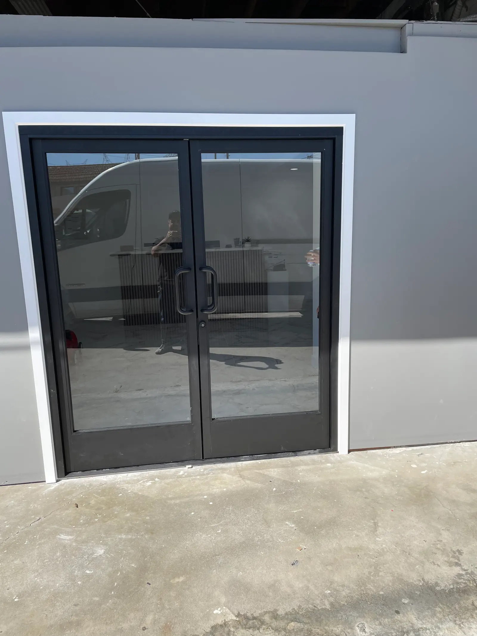 Dark-framed commercial storefront double doors with a full-height pull handle