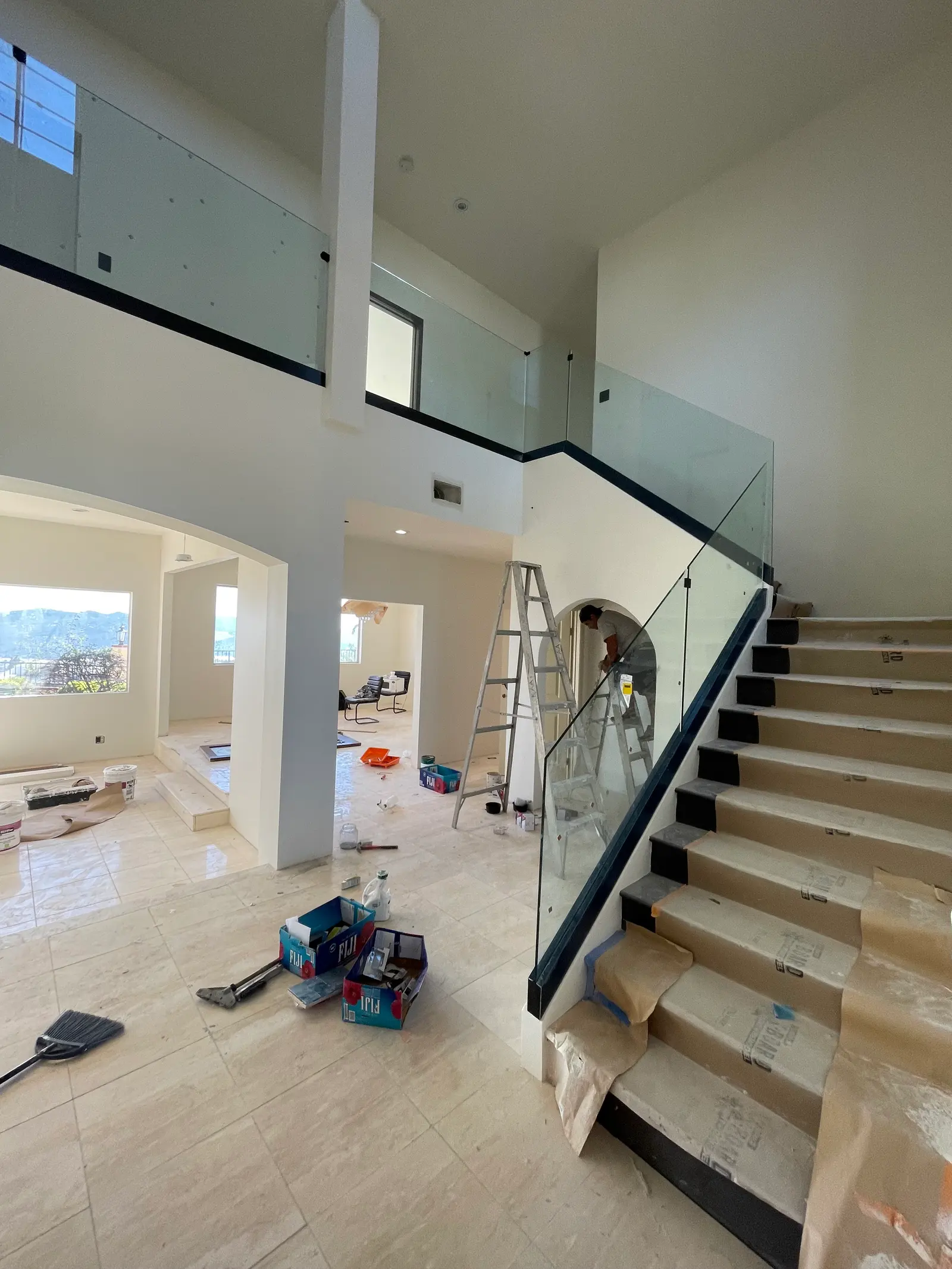 Glass railing with a black cap rail running up a staircase and along the floor above it