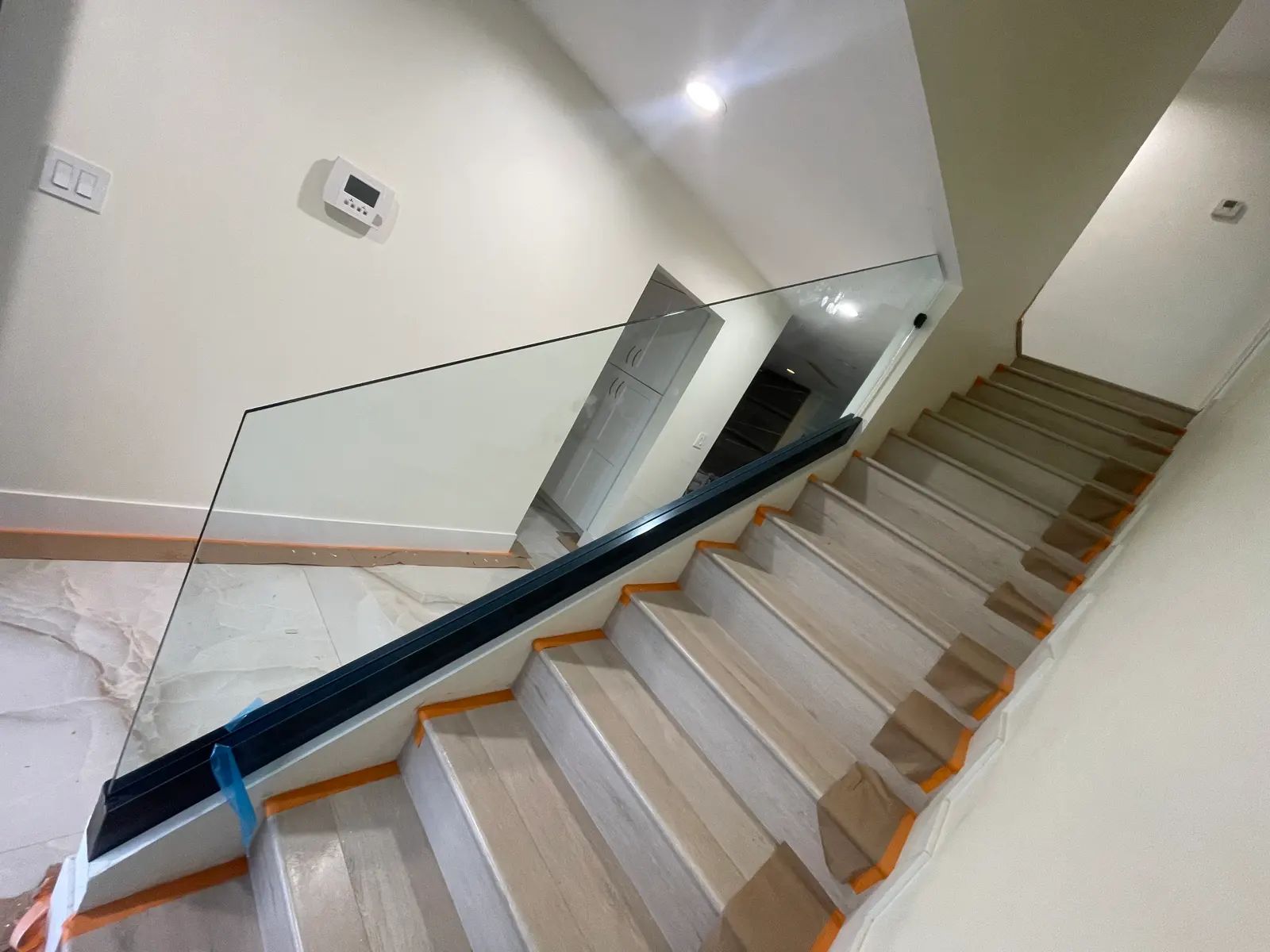 Glass stair railing with a black cap rail alongside light oak treads